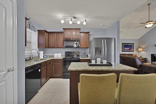 kitchen featuring light tile patterned floors, a kitchen island, open floor plan, black appliances, and a sink