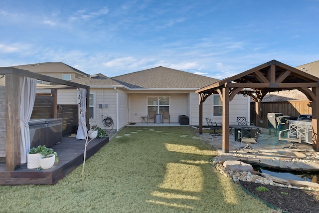 rear view of house with a lawn, roof with shingles, fence, a gazebo, and a patio area