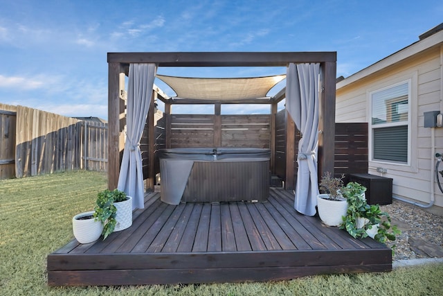 deck with a fenced backyard, a yard, and a hot tub