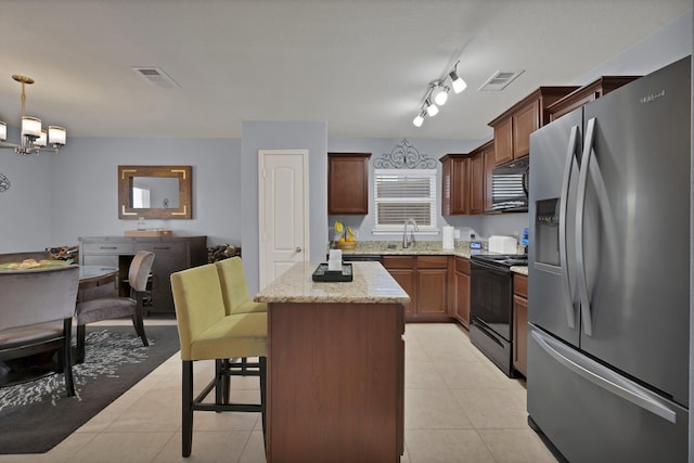 kitchen featuring black appliances, visible vents, a sink, and a center island