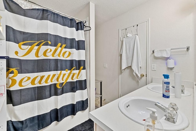 bathroom featuring a textured ceiling, double vanity, a shower with shower curtain, and a sink