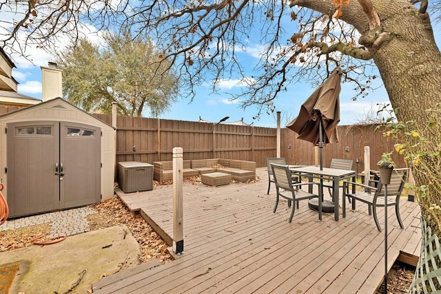 deck with a storage shed, a fenced backyard, outdoor dining space, and an outdoor structure