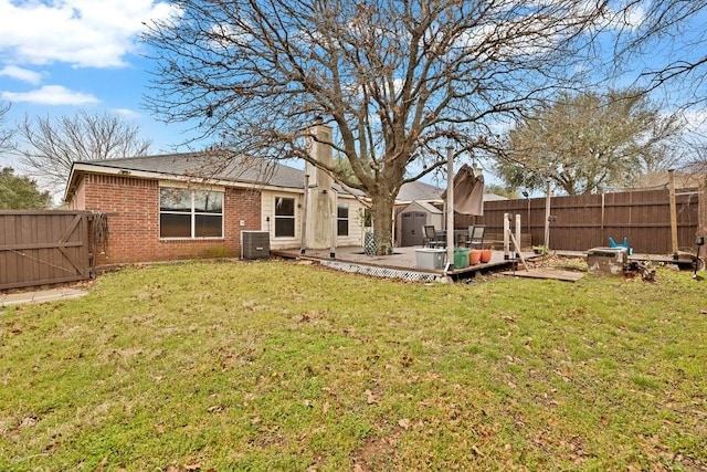 back of property with central air condition unit, a fenced backyard, a lawn, and brick siding