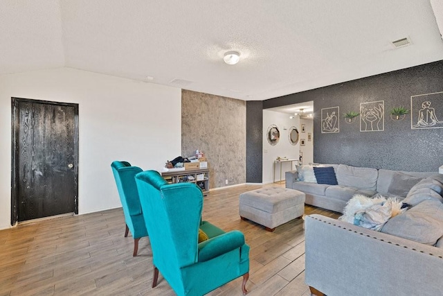 living area featuring visible vents, a textured ceiling, and wood finished floors