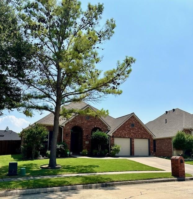 single story home with a front yard, concrete driveway, brick siding, and an attached garage