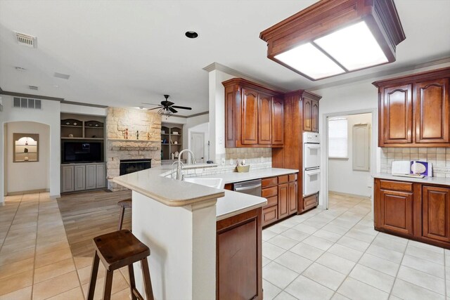 kitchen with white double oven, a breakfast bar area, open floor plan, a sink, and a peninsula