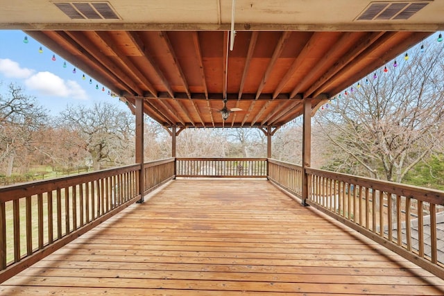 wooden terrace featuring visible vents and a ceiling fan