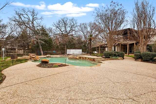 pool with a patio area, fence, and a jacuzzi