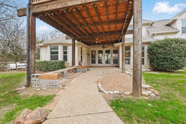 exterior space featuring ceiling fan, french doors, a shingled roof, and brick siding