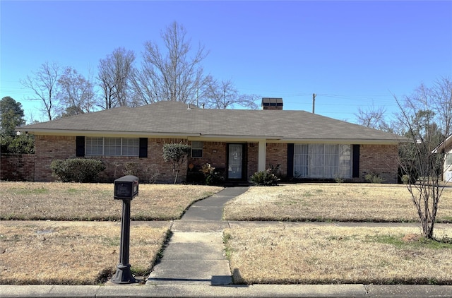 ranch-style house featuring a chimney and brick siding