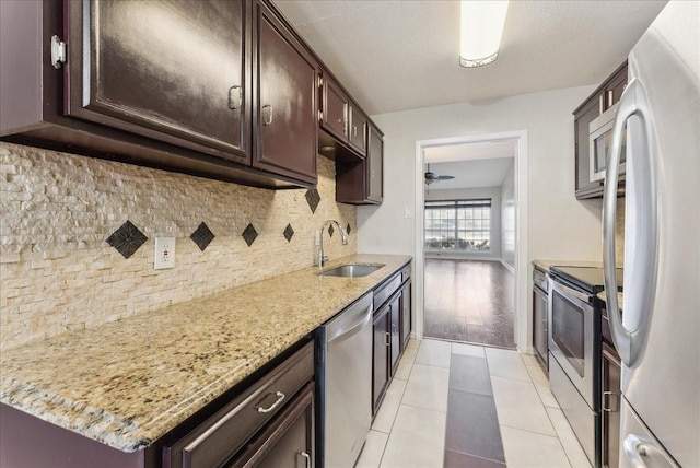 kitchen featuring tasteful backsplash, dark brown cabinets, light tile patterned floors, appliances with stainless steel finishes, and a sink