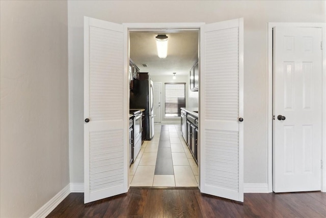 corridor featuring baseboards and light wood finished floors