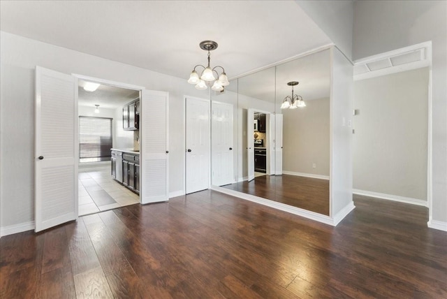 unfurnished dining area with a notable chandelier, baseboards, and wood-type flooring