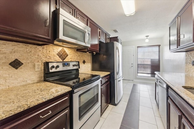 kitchen featuring light stone counters, visible vents, light tile patterned flooring, appliances with stainless steel finishes, and tasteful backsplash