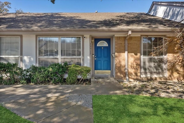 property entrance with brick siding and a shingled roof