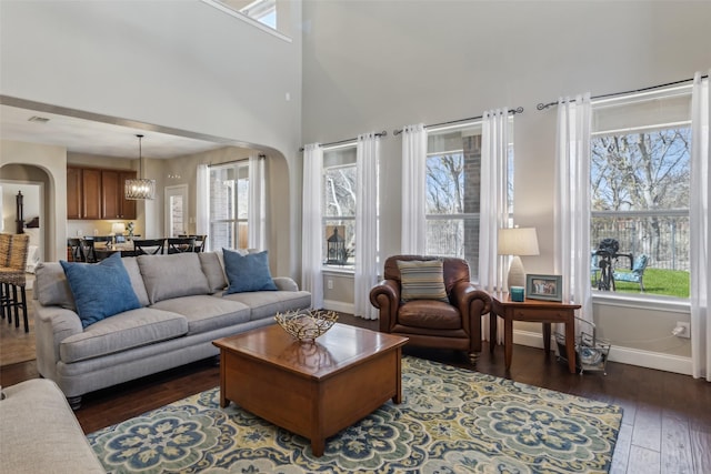 living room featuring baseboards, arched walkways, and dark wood-type flooring