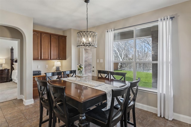 dining room featuring baseboards, arched walkways, and a notable chandelier