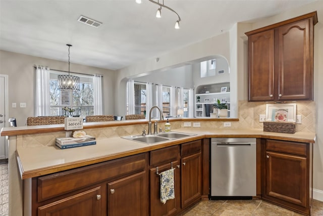 kitchen featuring light countertops, visible vents, backsplash, stainless steel dishwasher, and a sink