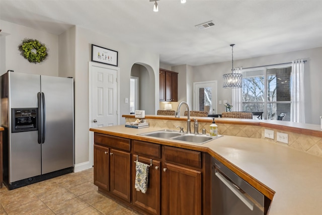 kitchen featuring a sink, visible vents, light countertops, appliances with stainless steel finishes, and decorative light fixtures