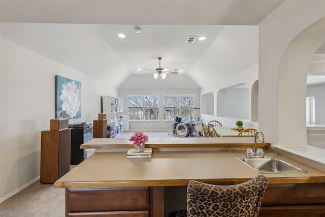 kitchen featuring light carpet, ceiling fan, open floor plan, vaulted ceiling, and a sink