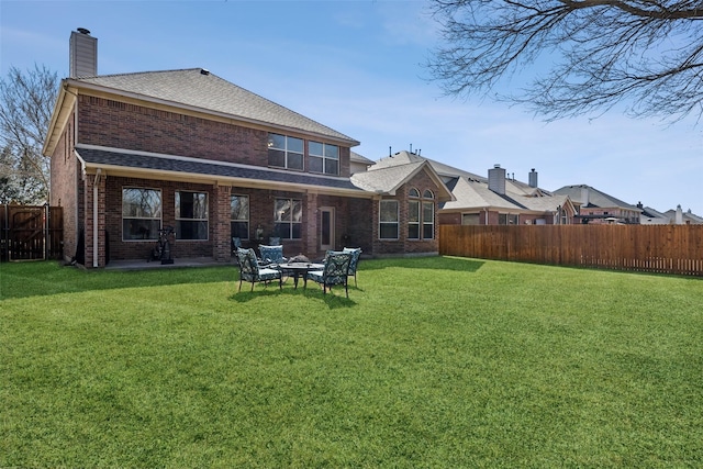 back of house featuring a fenced backyard, brick siding, a chimney, and a lawn