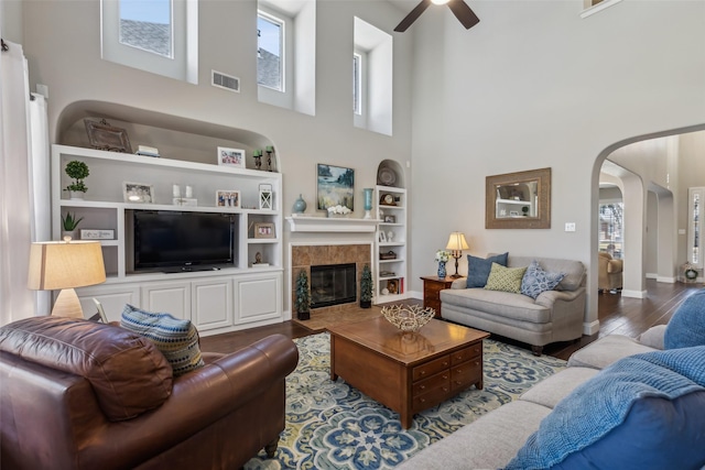 living area with arched walkways, a wealth of natural light, wood finished floors, and visible vents