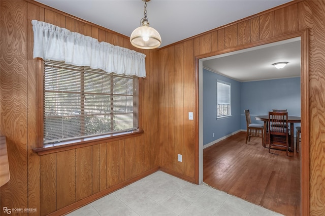 dining area with crown molding, wooden walls, and a wealth of natural light