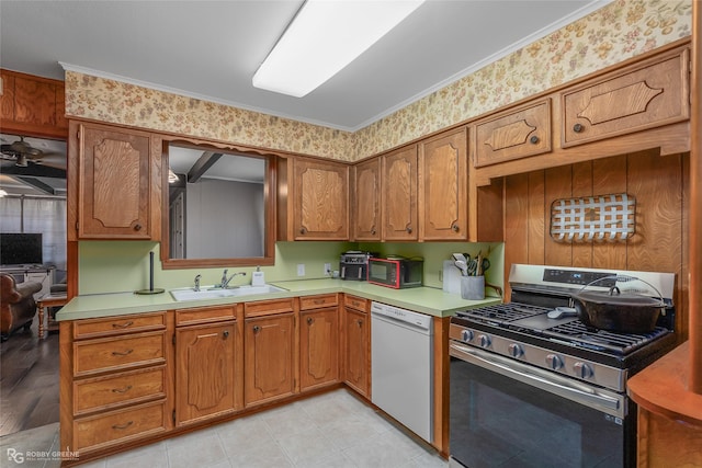 kitchen with dishwasher, brown cabinets, light countertops, a sink, and gas stove