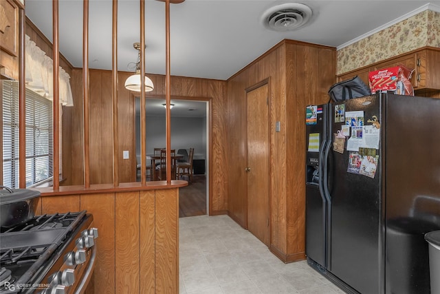 kitchen featuring brown cabinetry, visible vents, black fridge with ice dispenser, and stainless steel gas range oven