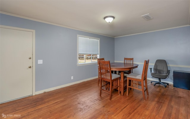 dining area with baseboards, wood finished floors, visible vents, and crown molding