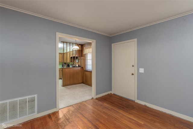 spare room featuring visible vents, crown molding, baseboards, and wood finished floors