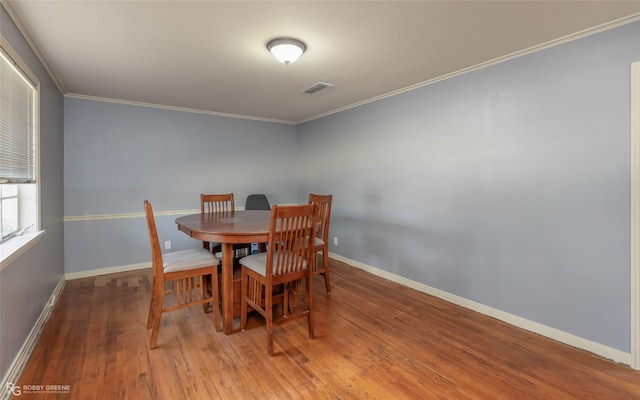 dining area with ornamental molding, wood finished floors, visible vents, and baseboards