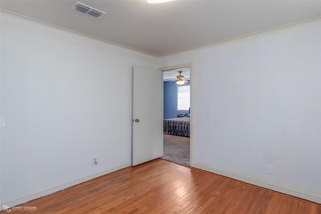 empty room featuring light wood-type flooring, visible vents, and baseboards