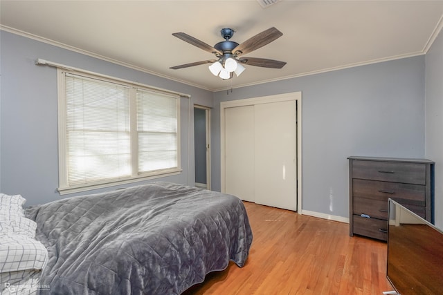 bedroom with ornamental molding, ceiling fan, light wood finished floors, and a closet