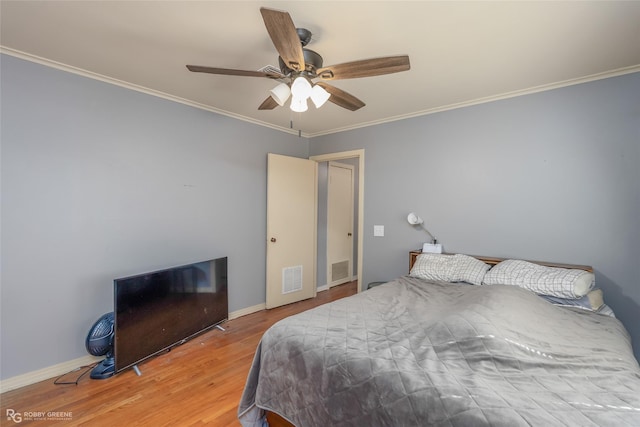 bedroom featuring baseboards, visible vents, wood finished floors, and ornamental molding