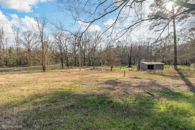 view of yard with a forest view, a rural view, fence, and an outdoor structure