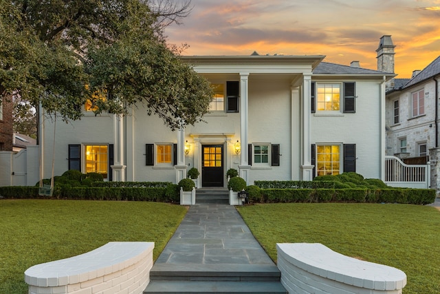 neoclassical home featuring brick siding and a lawn