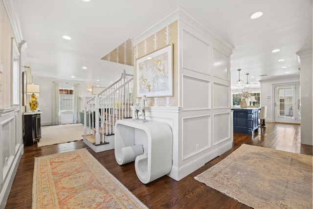 foyer featuring dark wood finished floors, stairs, crown molding, a decorative wall, and recessed lighting