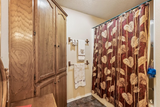 1579 County Road 2008 Unit F, Glen Rose, TX 76043 - bathroom with a textured ceiling, a shower with shower curtain, and baseboards