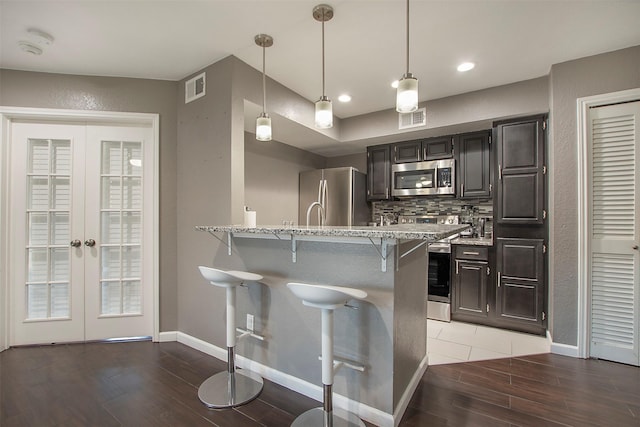 kitchen with appliances with stainless steel finishes, french doors, visible vents, and a kitchen breakfast bar