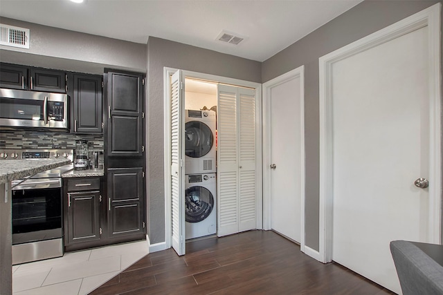 washroom featuring laundry area, visible vents, stacked washer / dryer, and wood finished floors