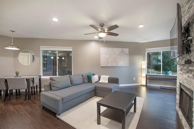 living area featuring ceiling fan, a stone fireplace, recessed lighting, wood finished floors, and baseboards