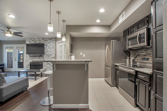 kitchen with stainless steel appliances, visible vents, a kitchen breakfast bar, open floor plan, and backsplash