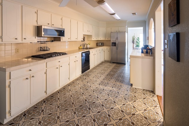 kitchen featuring ornamental molding, appliances with stainless steel finishes, a sink, and tile counters