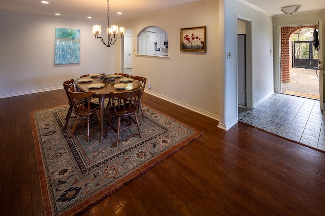 dining space featuring arched walkways, a chandelier, wood finished floors, and ornamental molding