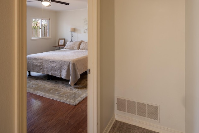 bedroom with baseboards, visible vents, ceiling fan, wood finished floors, and crown molding