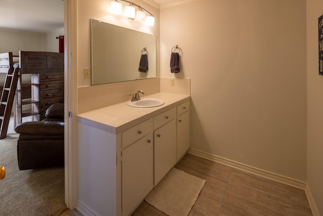 bathroom featuring baseboards, tasteful backsplash, vanity, and crown molding