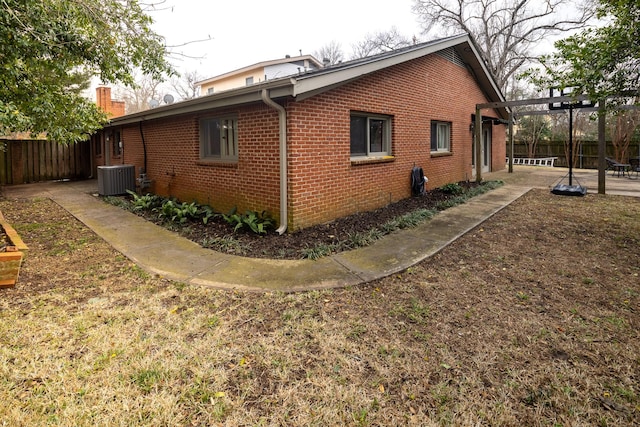 view of side of property with a patio, brick siding, and fence