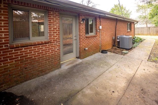 rear view of property with a patio area, brick siding, fence, and central air condition unit