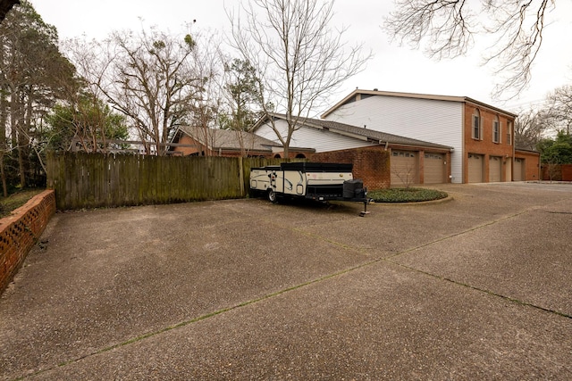 view of side of property featuring concrete driveway, brick siding, and fence